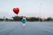 © VISTA by Westend61 - Girl with earth cut out and heart balloon standing in parking lot