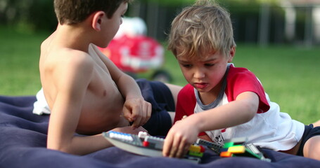 Wall Mural - Two brothers playing with toys outside in backyard