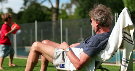 Retired senior older man enjoying retirement in backyard home garden during summer hot day