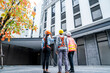 © Supavadee - Senior male froman and female staff and male crew members stand and watch building construction work at construction site.