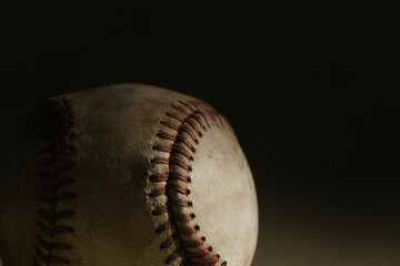 Wall Mural - Closeup view of old worn leather on used baseball ball in dark moody background.
