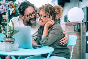 Wall Mural - People using computer together with love and friendship outdoor in garden home. Happy modern lifestyle with online connection. Man and woman surfing social media smiling and bonding. Couple use laptop