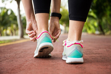 Wall Mural - runner woman tying up laces of shoes, getting ready to run for cardio and weight loss