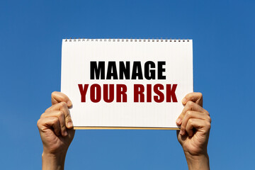 manage your risk text on notebook paper held by 2 hands with isolated blue sky background. this mess