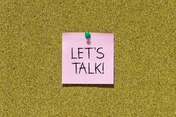 Poster - Let's talk text on pink post-it paper pinned on bulletin cork board. This message can be used in business concept about talking together.