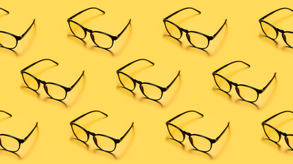 Modern black framed reading glasses or spectacles repeated on a bright yellow background with minimalist style.