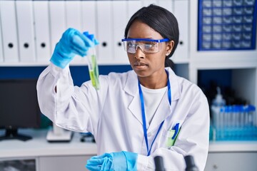 Canvas Print - Young african american woman scientist holding test tubes at laboratory