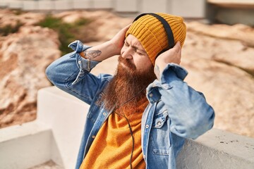 Sticker - Young redhead man listening to music sitting on bench at street