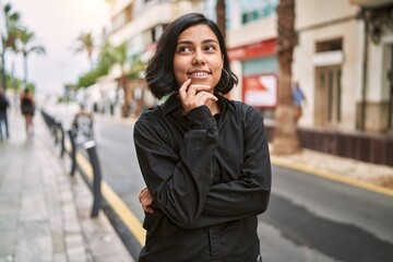 Wall Mural - Young latin woman smiling confident standing with arms crossed gesture at street