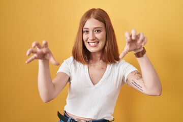 Canvas Print - Young redhead woman standing over yellow background smiling funny doing claw gesture as cat, aggressive and sexy expression