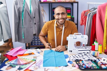 Poster - Young latin man tailor smiling confident cutting cloth at atelier