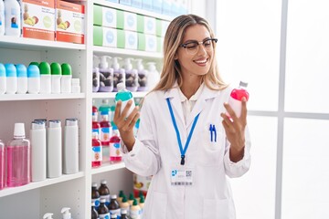 Poster - Young blonde woman pharmacist smiling confident holding medication bottles at pharmacy