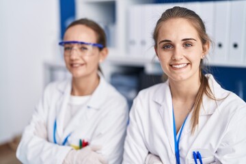 Wall Mural - Two women scientists smiling confident with arms crossed gesture at laboratory