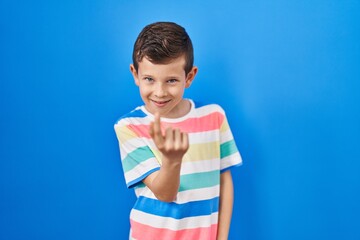 Young caucasian kid standing over blue background beckoning come here gesture with hand inviting welcoming happy and smiling