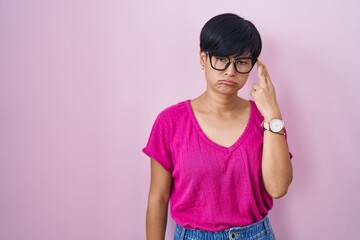 Sticker - Young asian woman with short hair standing over pink background shooting and killing oneself pointing hand and fingers to head like gun, suicide gesture.