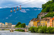 Isere river in Grenoble city skyline, Auvergne-Rhone-Alpes region, France. Pont Marius-Gontard bridge, Grenoble-Bastille Cable car (Telepherique) and Alps mountains on background