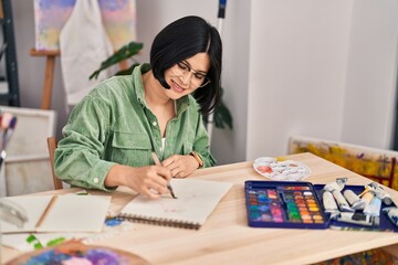 Wall Mural - Young chinese woman artist smiling confident drawing on notebook at art studio