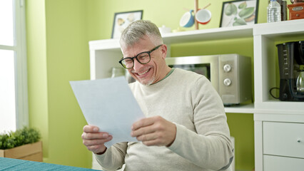 Sticker - Middle age grey-haired man reading document sitting on table at home