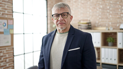 Wall Mural - Middle age grey-haired man business worker standing with relaxed expression at office