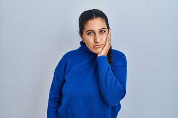 Sticker - Young hispanic woman standing over isolated background thinking looking tired and bored with depression problems with crossed arms.