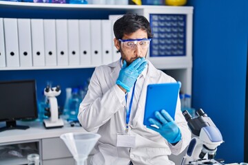 Poster - Handsome latin man working at scientist laboratory using tablet covering mouth with hand, shocked and afraid for mistake. surprised expression