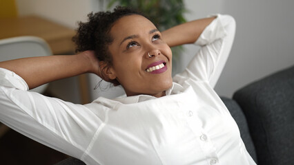 Sticker - African american woman relaxed with hands on head sitting on sofa at home