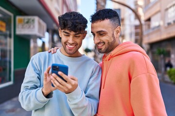 Wall Mural - Two man couple hugging each other using smartphone at street