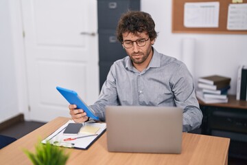 Canvas Print - Young hispanic man business worker using touchpad and laptop at office