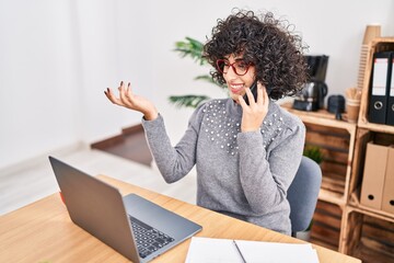 Poster - Young middle east woman business worker using laptop talking on smartphone at office