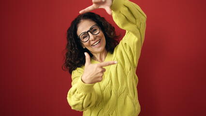 Sticker - Middle age hispanic woman smiling confident doing photo gesture with hands over isolated red background