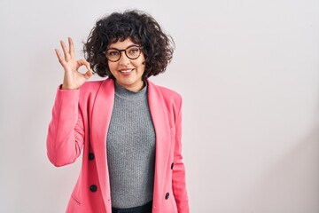 Poster - Hispanic woman with curly hair standing over isolated background smiling positive doing ok sign with hand and fingers. successful expression.