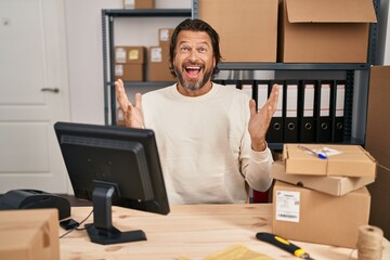 Wall Mural - Handsome middle age man working at small business ecommerce celebrating crazy and amazed for success with arms raised and open eyes screaming excited. winner concept