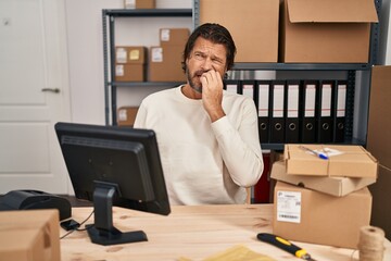 Canvas Print - Handsome middle age man working at small business ecommerce looking stressed and nervous with hands on mouth biting nails. anxiety problem.