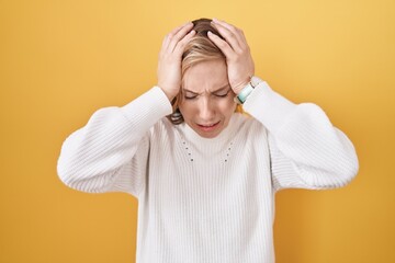 Canvas Print - Young caucasian woman wearing white sweater over yellow background suffering from headache desperate and stressed because pain and migraine. hands on head.