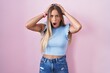 © Krakenimages.com - Young blonde woman standing over pink background crazy and scared with hands on head, afraid and surprised of shock with open mouth