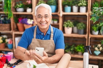 Canvas Print - Middle age grey-haired man florist smiling confident using smartphone at florist