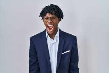 Poster - Young african man with dreadlocks wearing business jacket over white background angry and mad screaming frustrated and furious, shouting with anger. rage and aggressive concept.