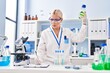 © Krakenimages.com - Young blonde woman wearing scientist uniform holding bottle at laboratory