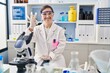 © Krakenimages.com - Hispanic girl with down syndrome working at scientist laboratory smiling positive doing ok sign with hand and fingers. successful expression.