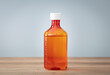Bottle with liquid medicine. Transparent orange vial with lid on neutral background. Stop your cold today. Copy space for text or image.