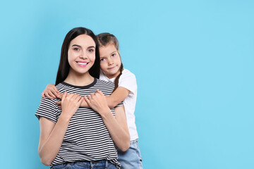 Sticker - Happy woman with her cute daughter on light blue background, space for text. Mother's day celebration