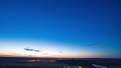 Wall Mural - Time-lapse sunrise over beautiful lake. Water surface in fast motion. Warm sky with rolling clouds. Trees silhouette woodland on horizon. Early morning shot in timelapse. Bright sun rises over skyline