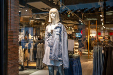 A Female Mannequin In A Denim Jacket In A Glass Showcase Of A Fashionable Youth Clothing Store. Style And Beauty. Close-up.