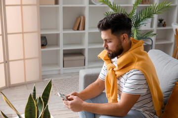 Canvas Print - Young bearded man using mobile phone at home