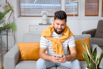 Canvas Print - Young bearded man using mobile phone at home