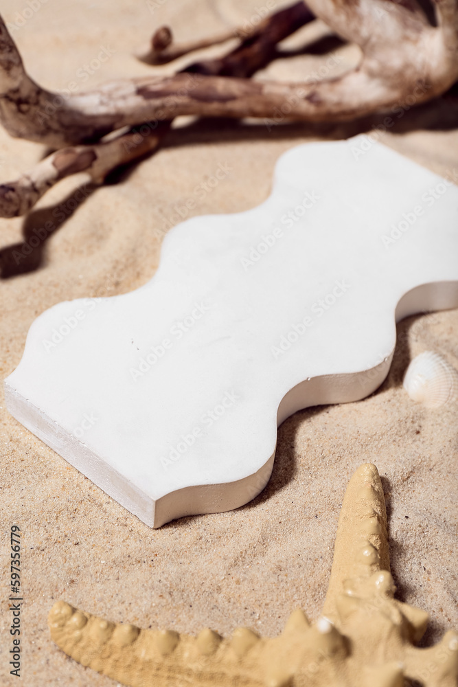 Decorative plaster podium, seashell, starfish and tree branch in sand