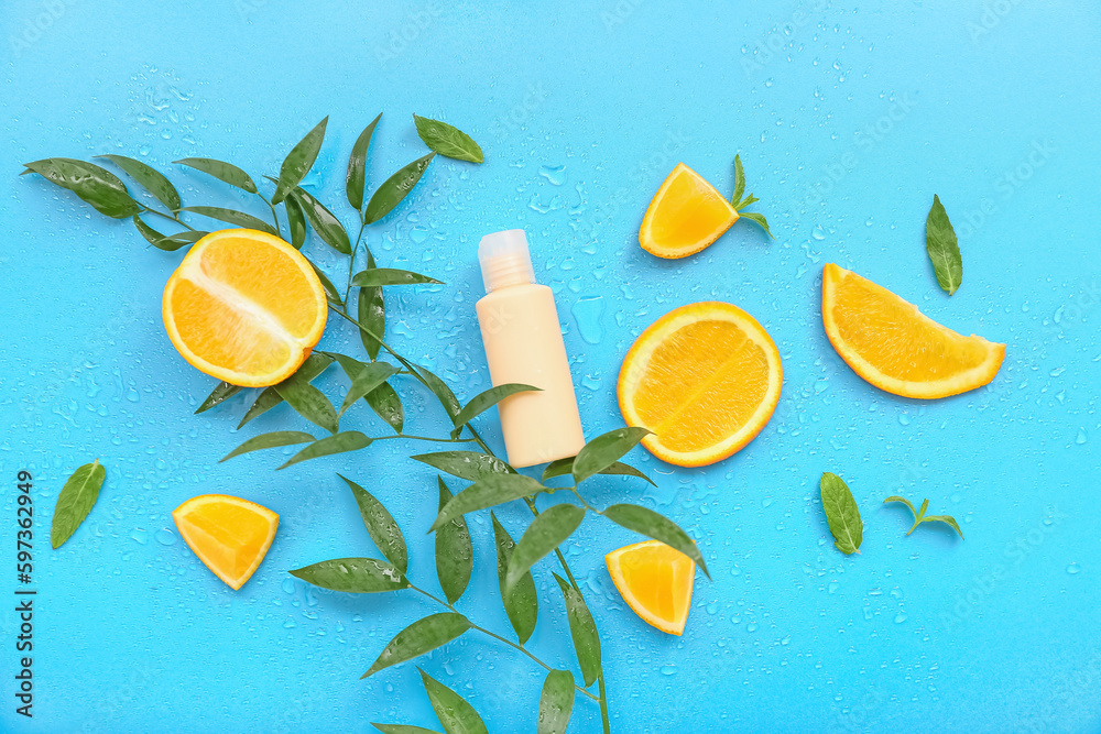 Cosmetic bottle with oranges and plant branch on blue background