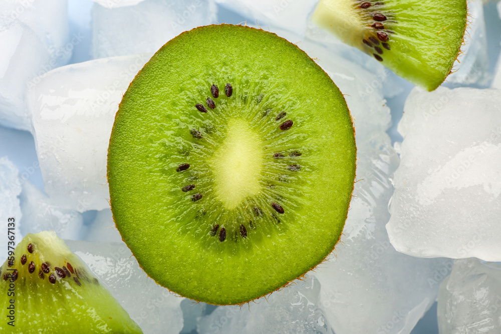 Sliced fresh kiwi and ice cubes on blue background