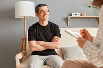 Psychologist with clipboard advising patient in clinic smiling man enjoying consultation solving mental problems smiling , psychotherapy session.