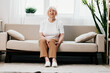 © SHOTPRIME STUDIO - Elderly woman severe pain in her leg sitting on the couch, health problems in old age, poor quality of life. Grandmother with gray hair holds on to her sore knee, problems with joints and ligaments.
